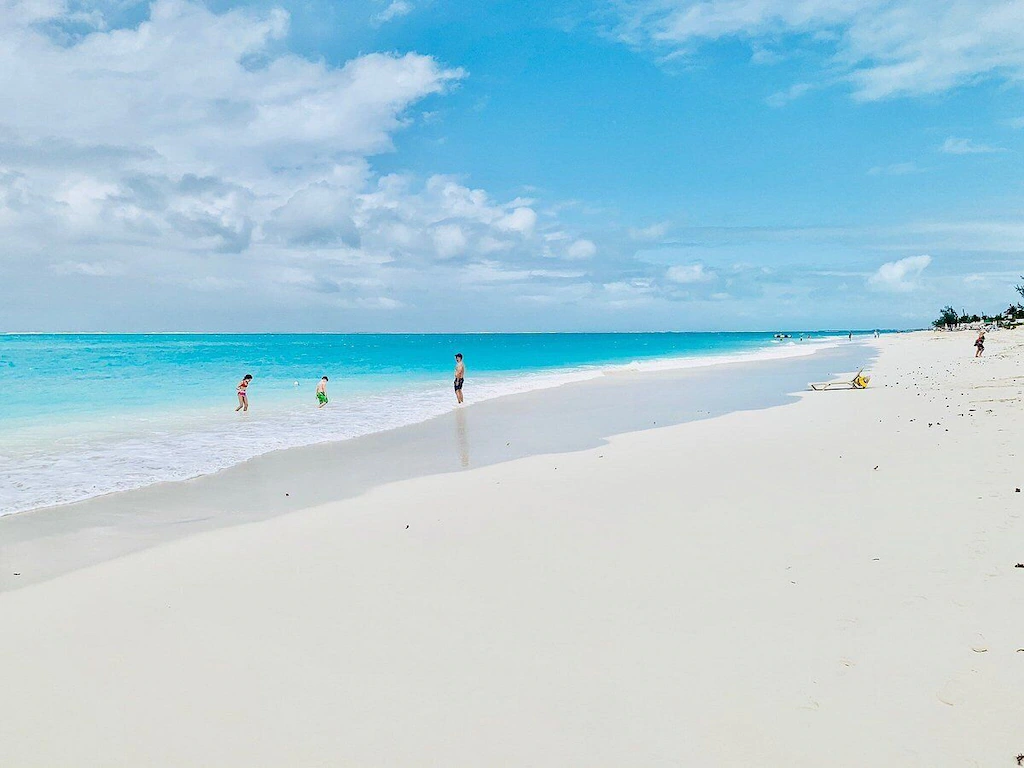 A beach with people walking on it and the ocean in the background.