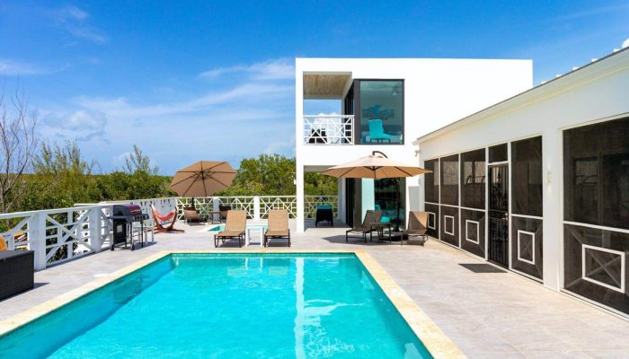 Modern villa with pool and patio umbrellas.