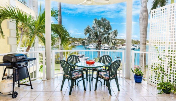 Balcony with chairs overlooking tropical waterfront.