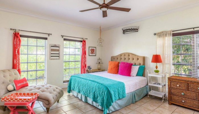 Bright bedroom with colorful decor and windows.