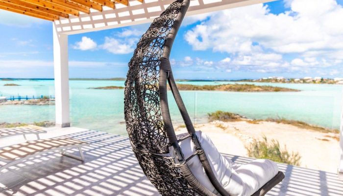 Hanging chair overlooking turquoise ocean view.