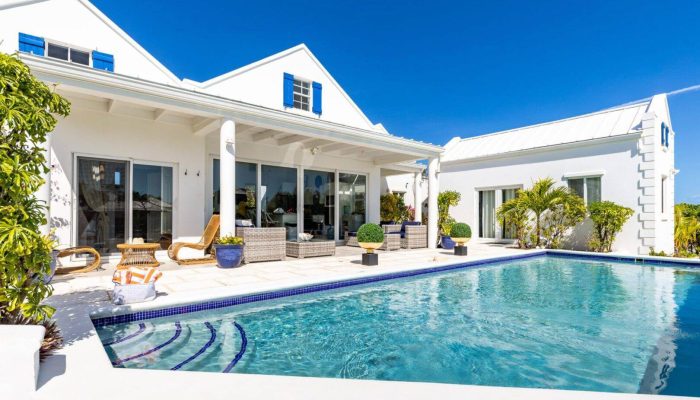 White villa with pool and patio furniture.