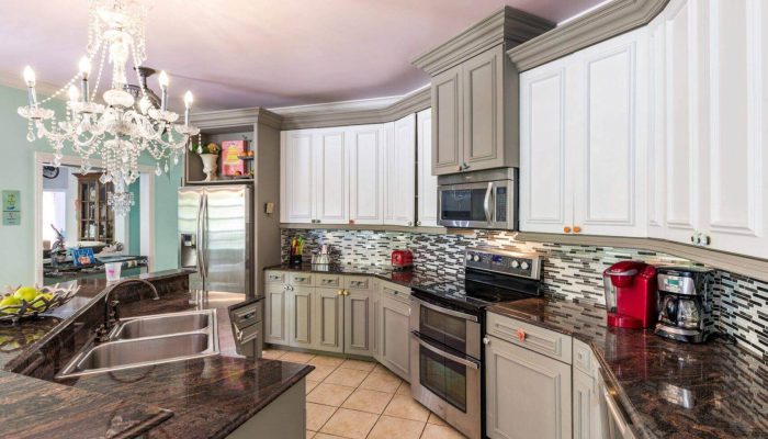 Modern kitchen with chandelier and dark countertops.
