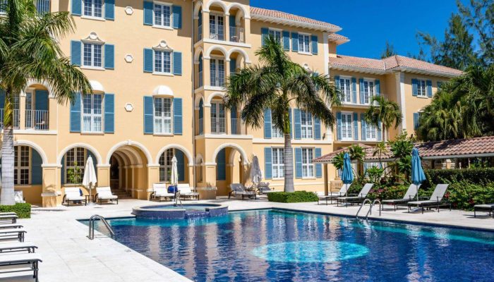 Yellow building with pool and palm trees.