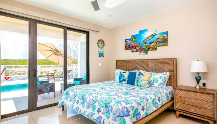 Bright bedroom with poolside view and artwork.