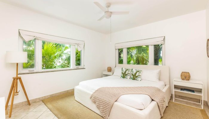 Bright bedroom with large windows and plants.