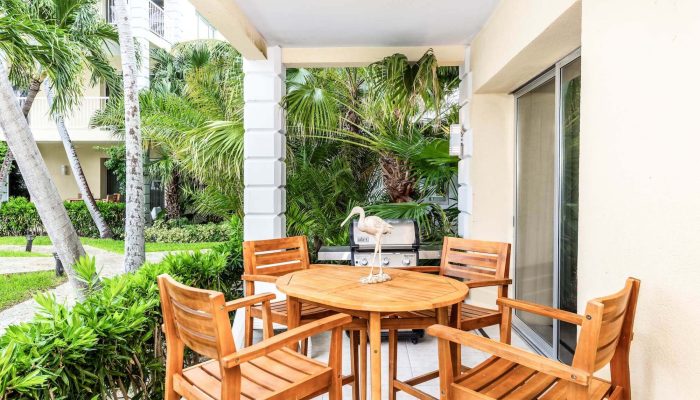 Tropical patio with wooden furniture and greenery.