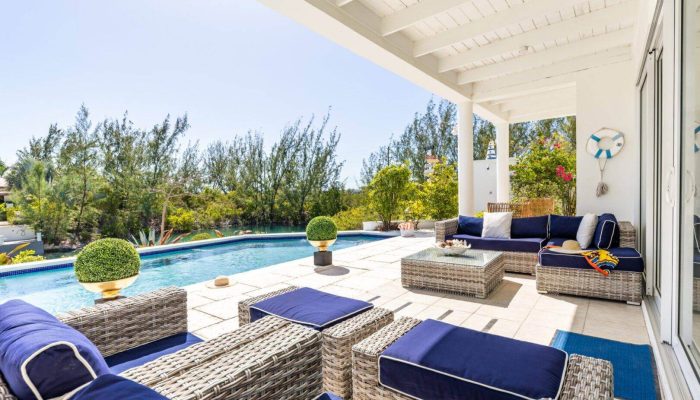 Poolside patio with wicker furniture and greenery.