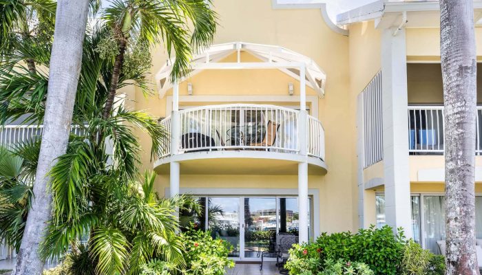 Yellow building with balcony and palm trees.