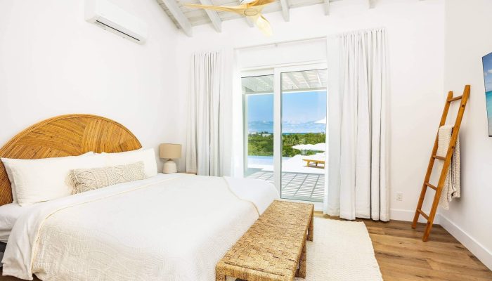 Bright ocean-view bedroom with wicker headboard