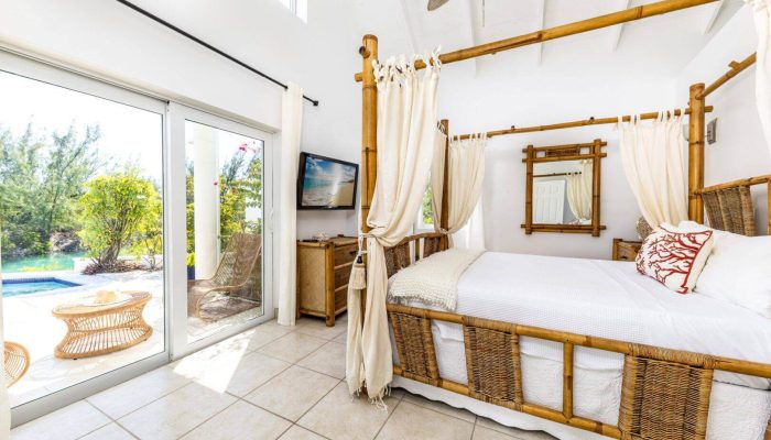 Bright bedroom with canopy bed and pool view.