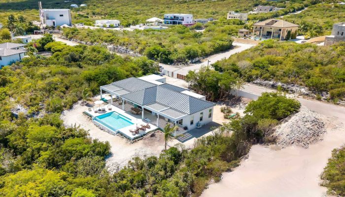 Aerial coastal villa with pool and beach