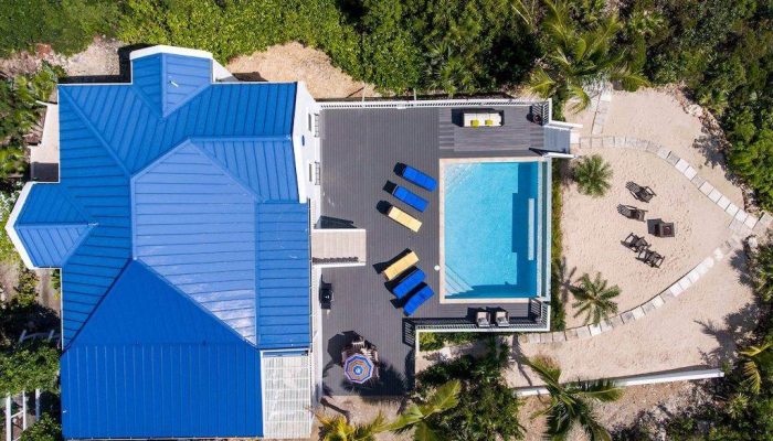Aerial view of blue-roof villa with pool