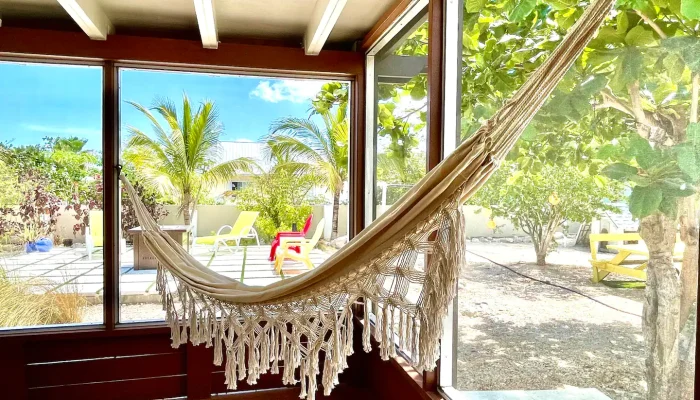Hammock in sunlit porch with garden view.