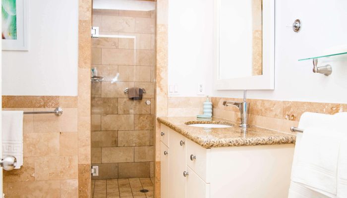 Beige tiled bathroom with glass shower and vanity