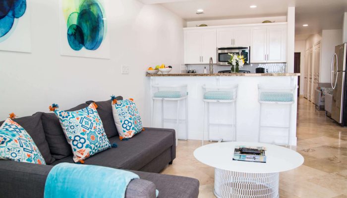 Modern living room with kitchen and bar stools.
