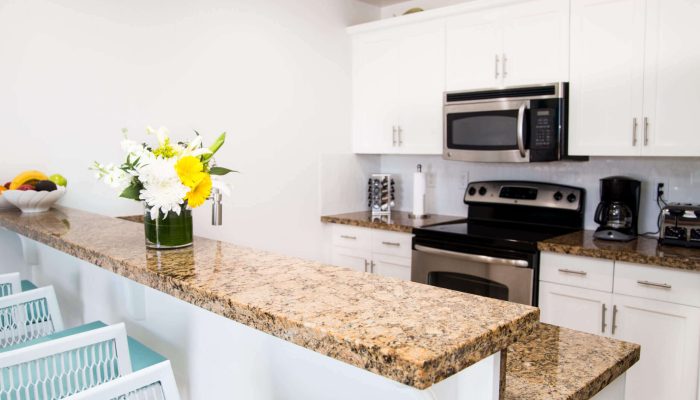 Modern kitchen with granite countertops and flowers.