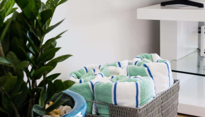 Towels in basket beside green plant.
