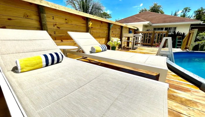 Poolside lounge chairs with striped towels.