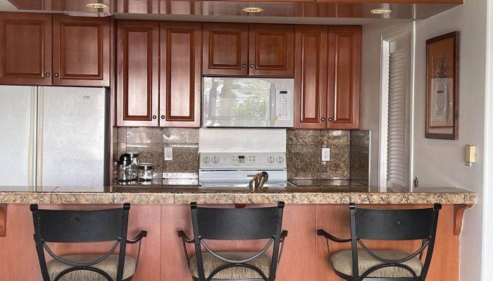 Kitchen with bar stools and wooden cabinets.